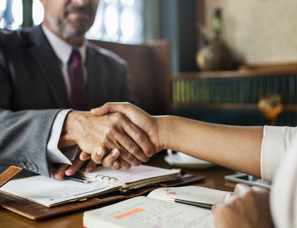 An attorney shaking hands with a client across a desk